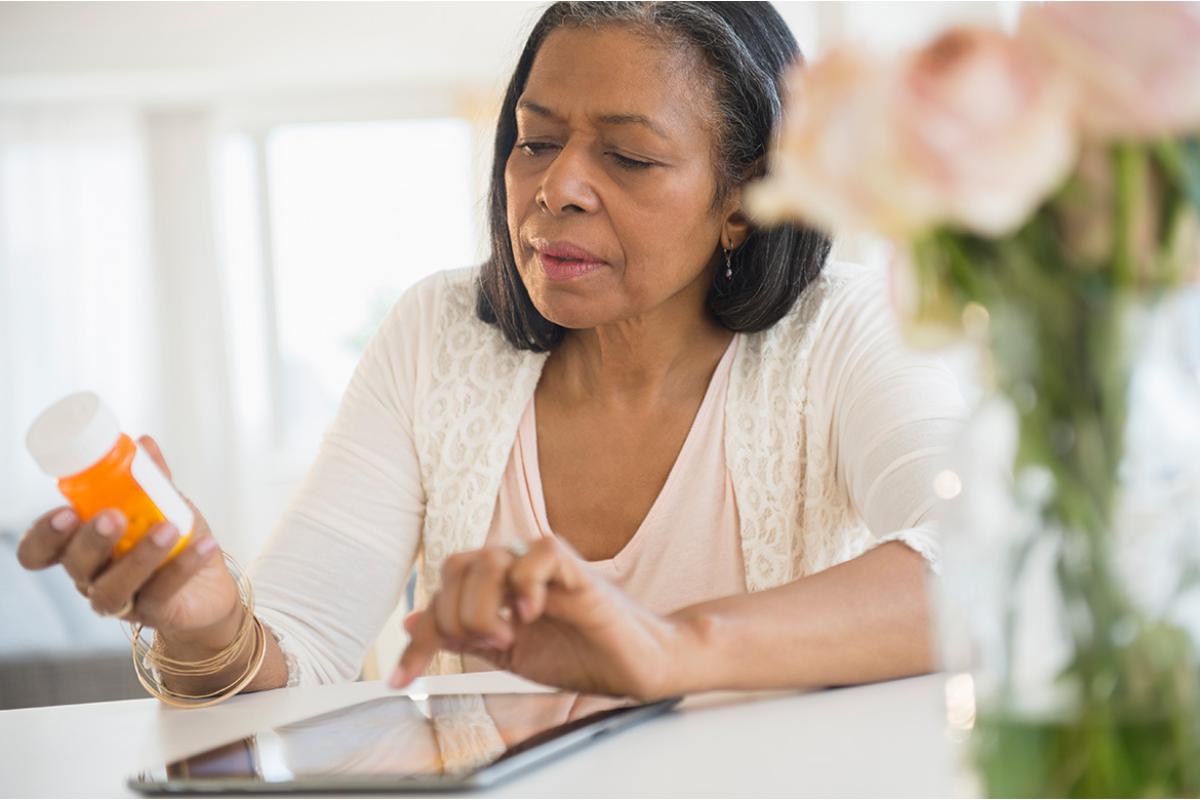Person looking at medication and using a tablet 